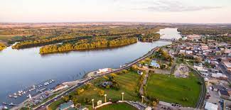 an image from the sky of a small town on a wide river at dusk.