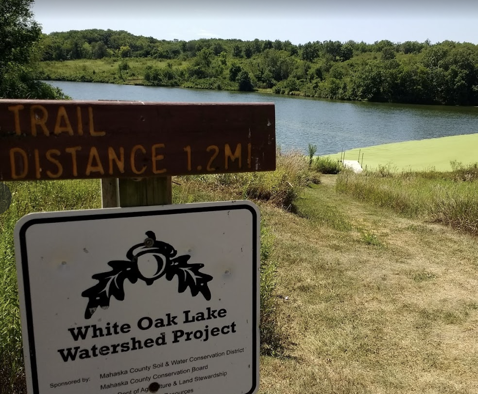 A sign with a lake in the. background during summer.