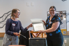 One woman hands an award to another woman.