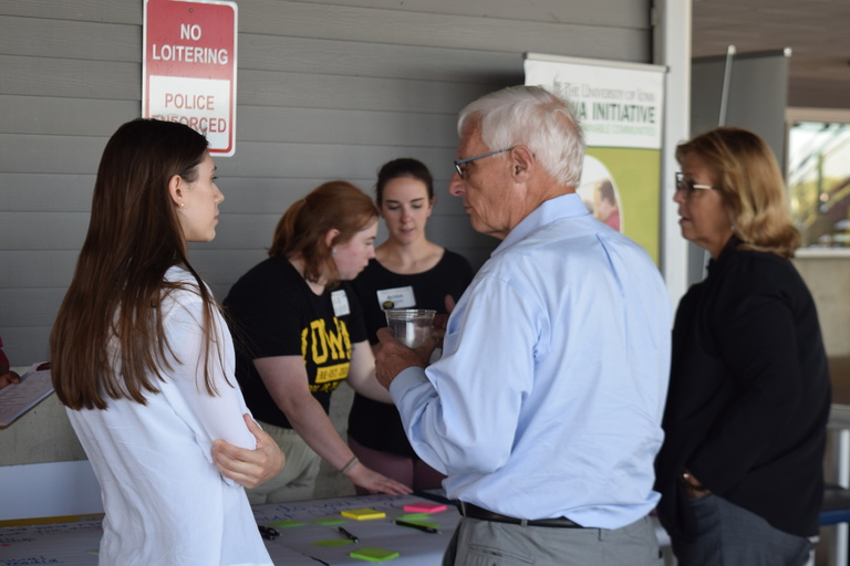 Three young women talk with an older couple.