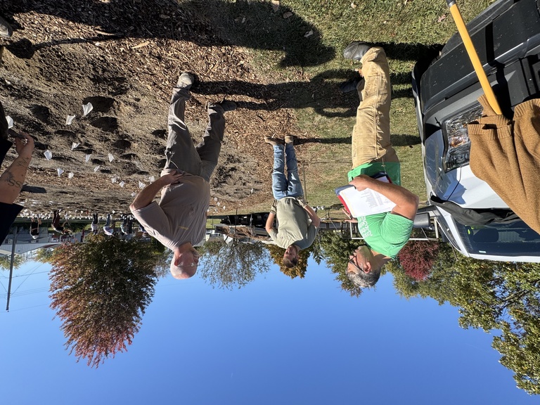 three men stand outside talking by a work site